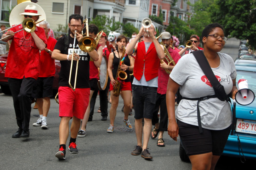 Deidra Montgomery, one of the festival organizers, walks with the Second Line Social Aid and Pleasure Society Brass Band during the festival's concluding parade. Second Line is a New Orleans-style street band based in Somerville and Cambridge that combines music with social action, performing at protests and peace rallies, as well as helping organize Somerville’s annual Honk festival of activist street bands. (Greg Cook)