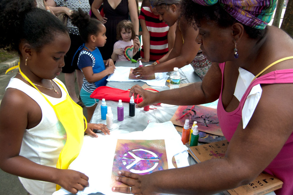Tanya Nixon-Silberg (right) of Wee The People helps kids stencil T-shirts at their "Protestival" at Boston's Mozart Park, July 8, 2017. (Greg Cook)