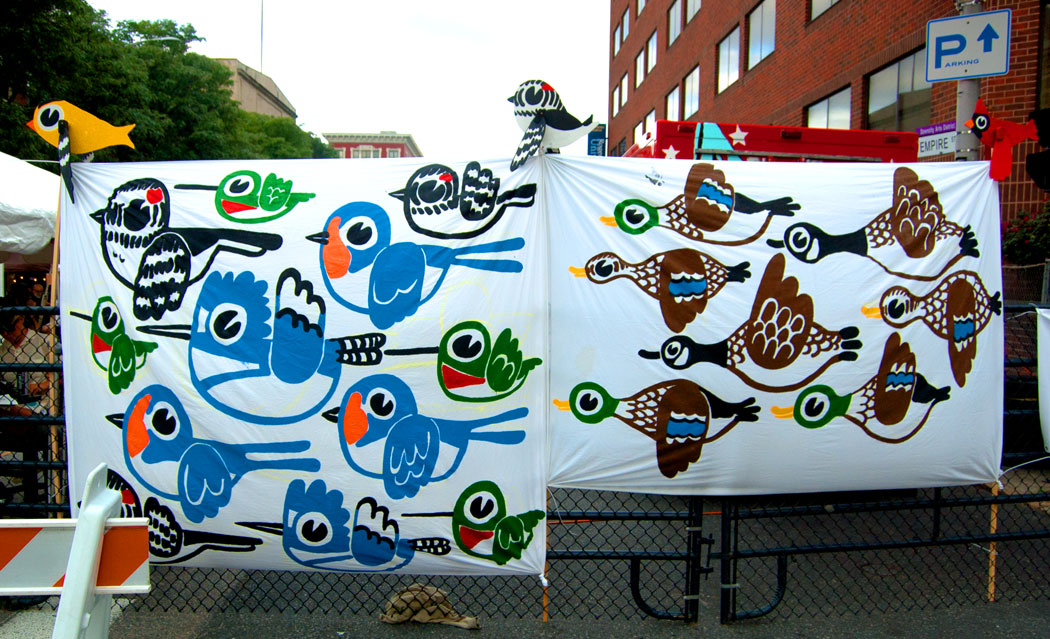 "Birds Respect No Borders" banners painted by Greg Cook on Foo Fest main gate. Whirligigs on top designed by Kari Percival and painted by Greg Cook (Greg Cook)