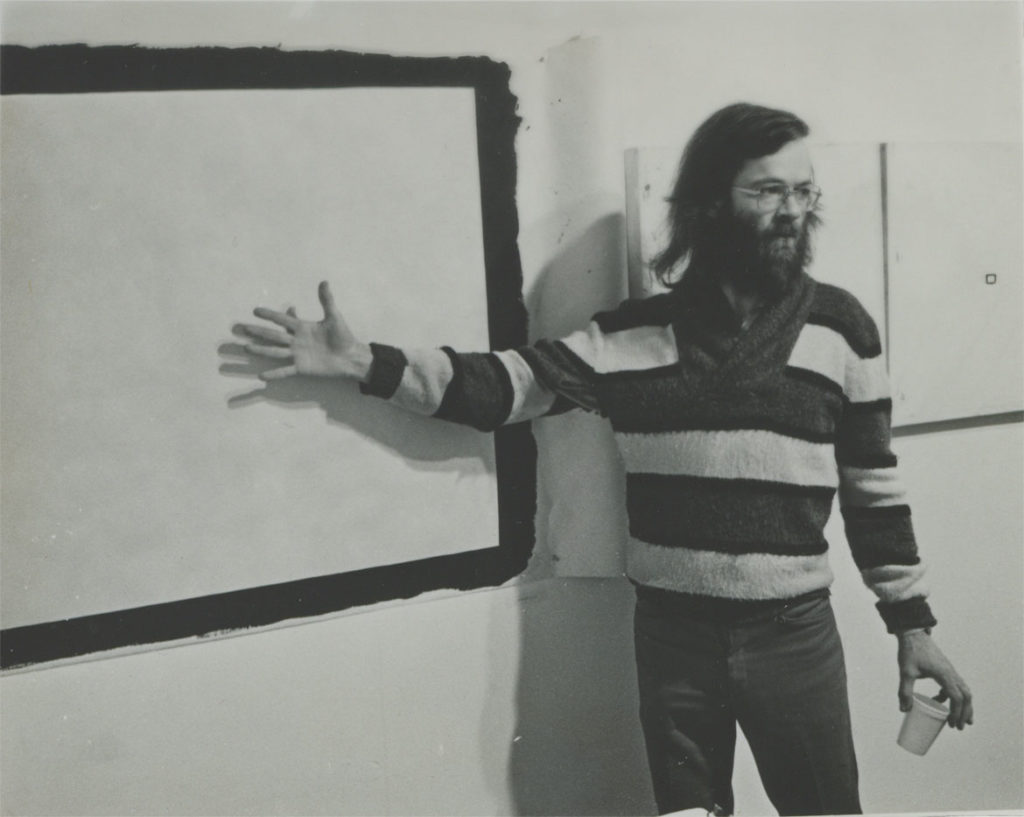 Tony Conrad in front of "Yellow Movie 2/2/73"(1973) and two "YellowMovie—35mm Format canvases" (1973), in his retrospective exhibition, Hallwalls Contemporary Arts Center, Buffalo, New York, December 1977. (Photo: Kevin Noble)