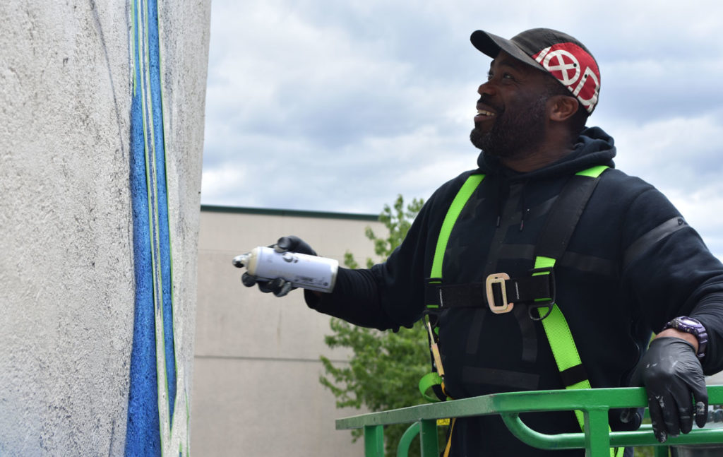 Rob "ProBlak" Gibbs paints his "Breathe Life 3" mural at 808 Tremont St., Boston, May 24, 2019. (Greg Cook)