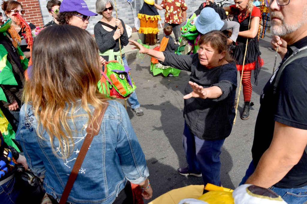 Sara Peattie advises those marching in the Honk Parade with the Puppeteers Cooperative before it begins, Oct. 13, 2019. (Greg Cook photo)