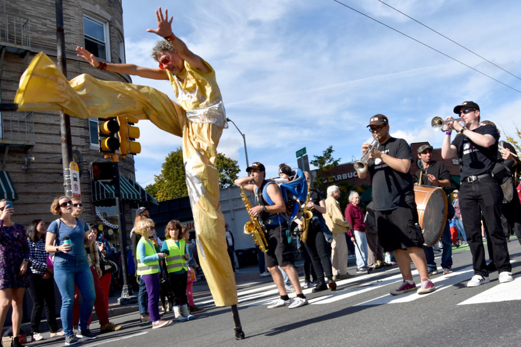 Stilter Shawn Morrisey dances in front of Boston's Dirty Water Brass Band during the Honk Parade, Oct. 13, 2019. (Greg Cook photo)