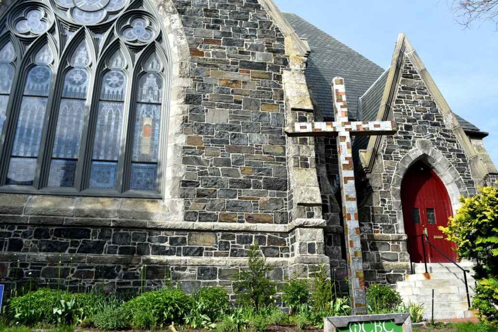 Old Cambridge Baptist Church mass shootings cross: "This cross is an evolving witness to the lives lost in 2018 due to mass shootings in the U.S. It is our sign of protest against the love of money and guns being valued over human lives. This death-dealing evil must end. Resurrection of peace and justice must persist." May 9, 2019. (Greg Cook photo)