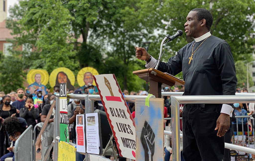 Protest icons seen behind Bishop Brian Greene of Pentecostal Tabernacle as he speaks at the Movement Continues rally at Cambridge Common, June 7, 2020. (Photo: Marc Levy / Cambridge Day)