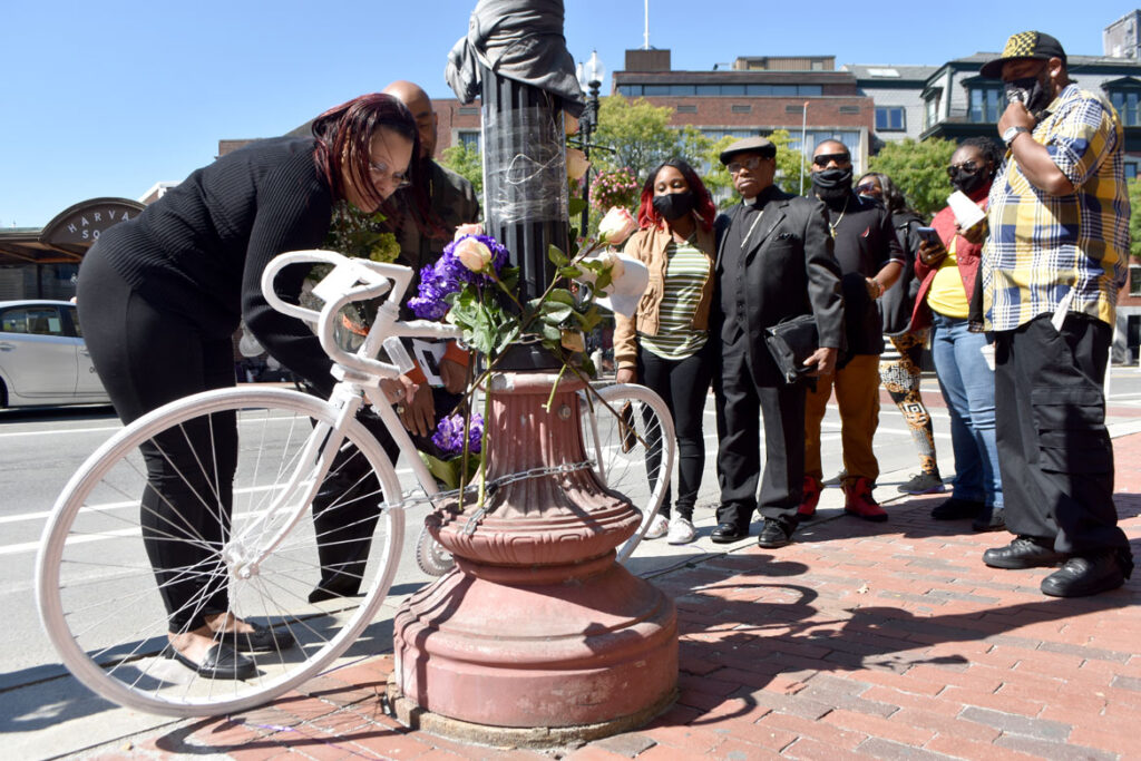 Donyell Chase-Willis (left) and other family members of Darryl Willis, who was fatally struck by a truck in Cambridge's Harvard Square on Aug. 18, place flowers on a ghost bike set there on Sept. 19, 2020. (© Greg Cook photo)