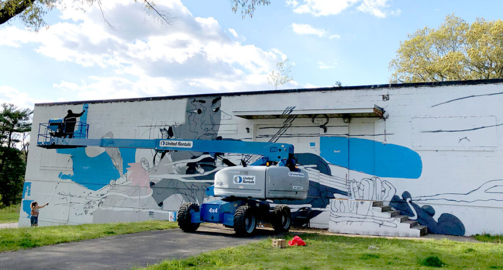 Cedric "Vise1" Douglas painting his mural at the former Medfield State Hospital, May 2021. (Courtesy Cultural Alliance of Medfield)