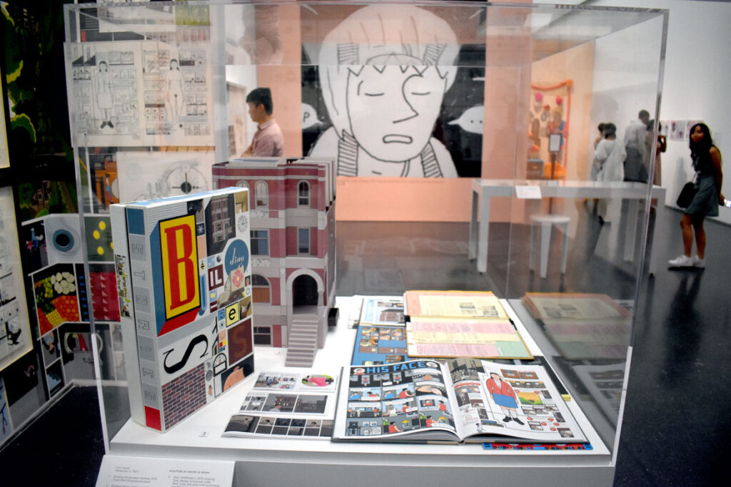 Chris Ware's “Building Stories” comics in foreground with enlarged John Porcellino panel in background. In “Chicago Comics” at Chicago’s Museum of Contemporary Art, July 3, 2021. (©Greg Cook photo)