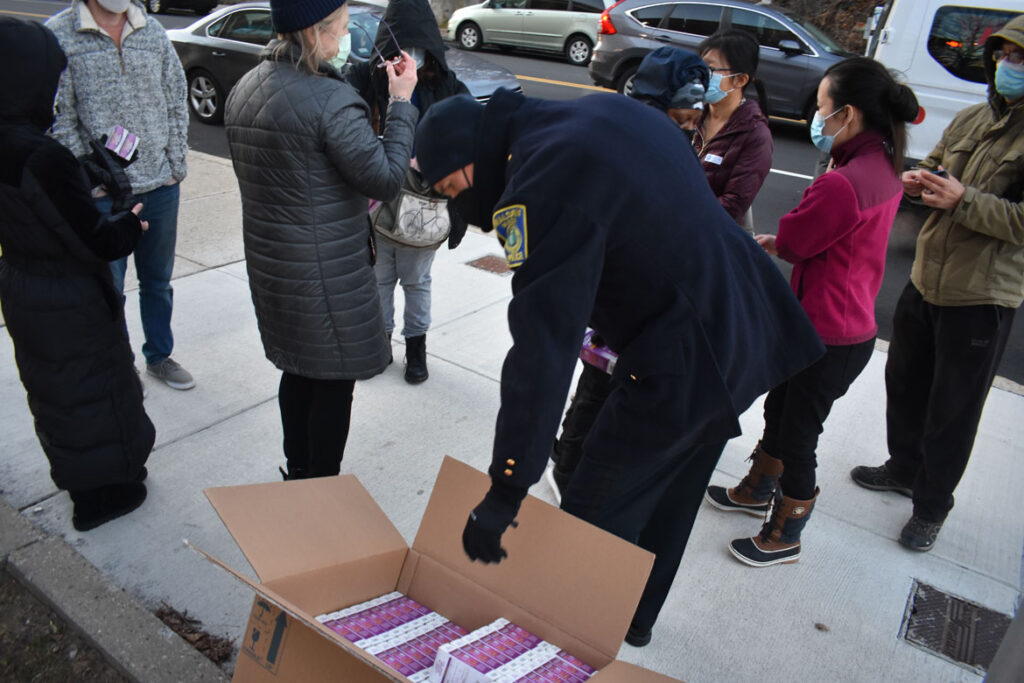 Malden Police Cheif Kevin Molis helping the city's Board of Health distribute free covid rapid test kits at Malden's Salemwood School, Jan. 4, 2022. (©Greg Cook photo)