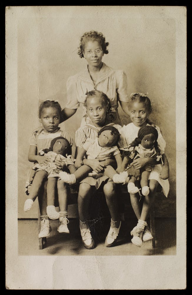 Unidentified photographer, Woman and children with Black cloth dolls, 1942.