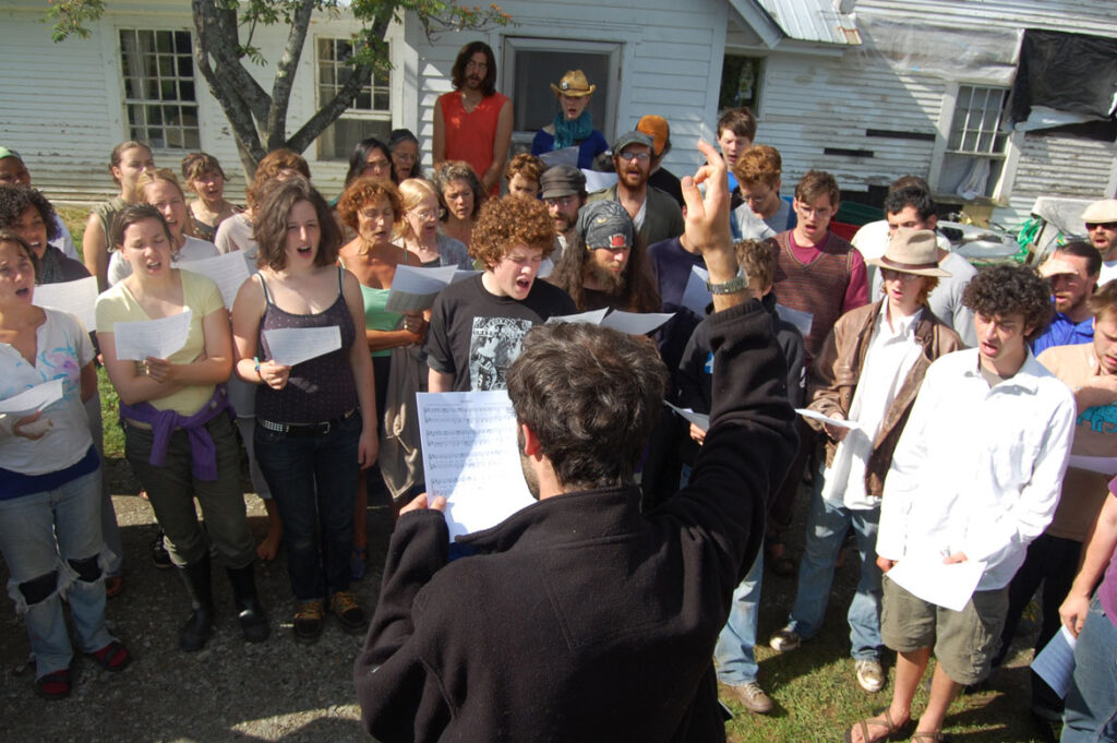 Genevieve Yeuillaz (center left in green top) participating in Bread and Puppet morning singing rehearsal, Glover, Vermont, Aug. 9, 2008. (©Greg Cook photo)