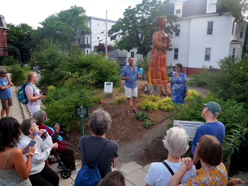 Fermin Castro (center) speaks about his sculpture "We Are Still Listening," 2022, at a reception at Symphony Park, Somerville, July 14, 2022. (©Greg Cook photo)