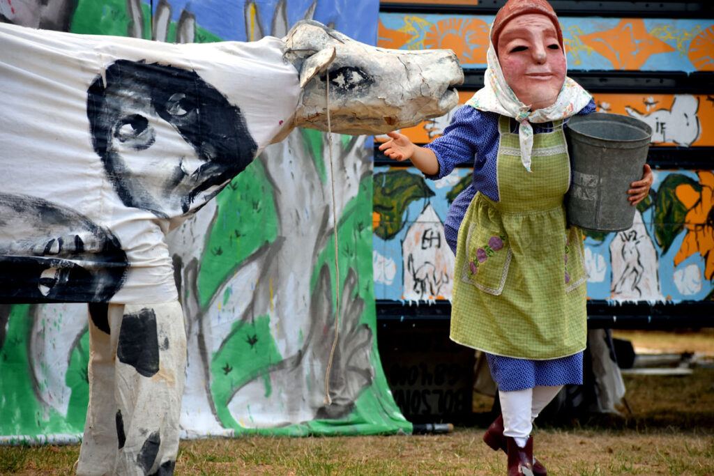Bread and Puppet Theater performs an act criticizing poor treatment of farm workers. From its “Apocalypse Defiance Circus” on Cambridge Common, Sept. 4, 2022. (© Greg Cook photo)