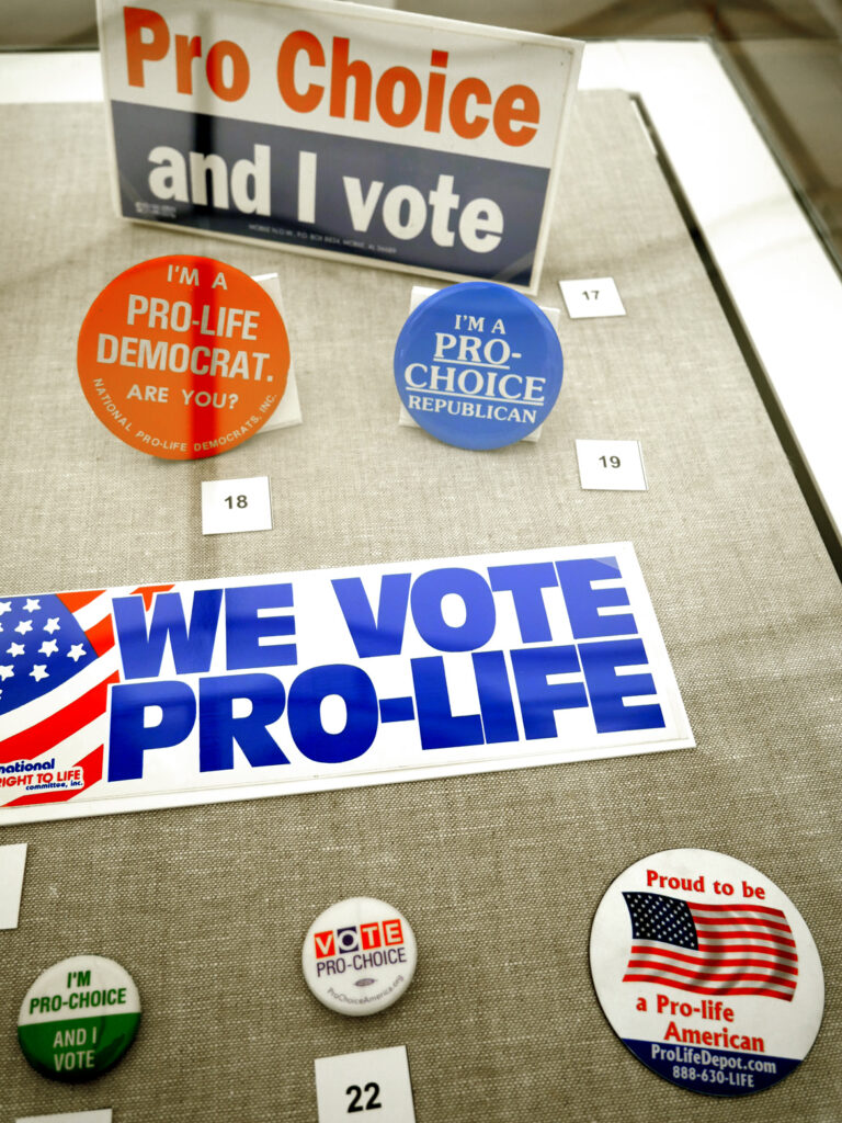 Buttons and bumperstickers in "The Age of Roe: The Past, Present, and Future of Abortion in America" at Harvard Radcliffe Institute Schlesinger Library's Poorvu Gallery.