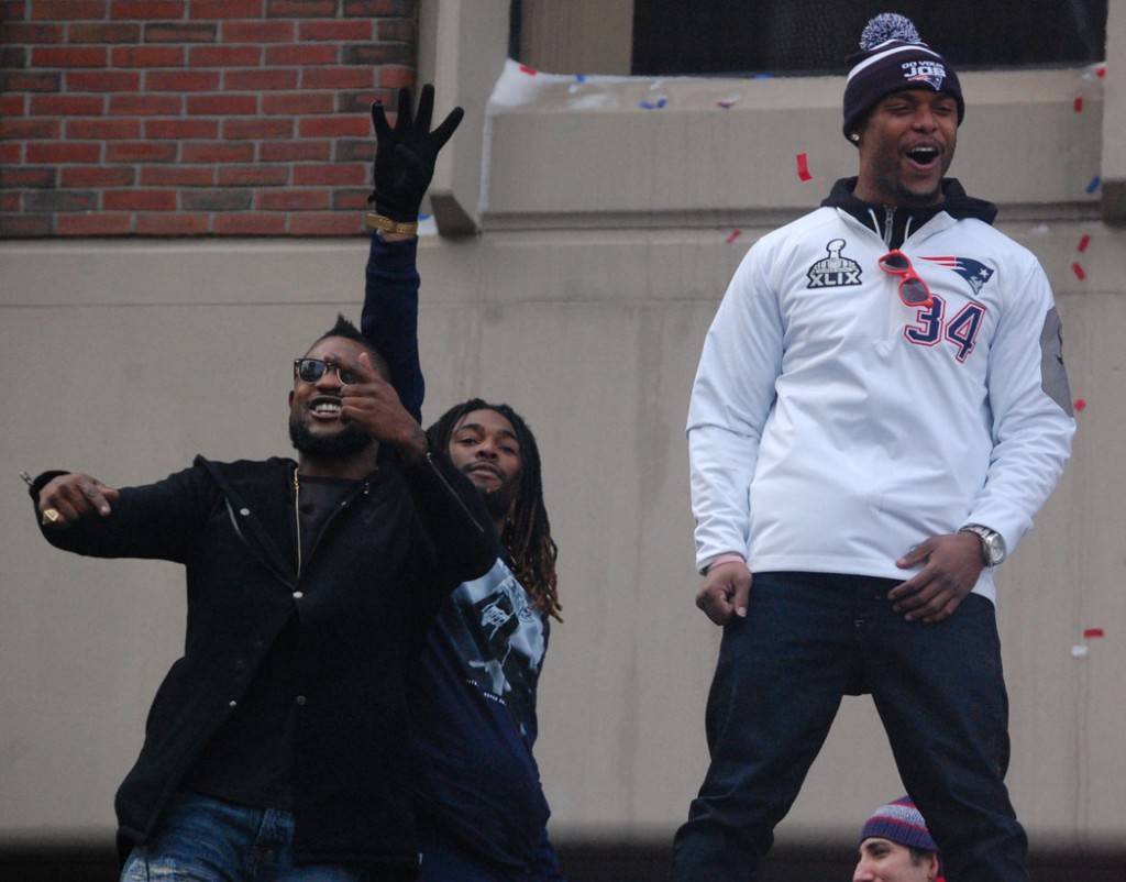 Steven Ridley (from left), Brandon Bolden and Shane Vereen celebrate as they roll past City Hall Plaza. (Greg Cook)