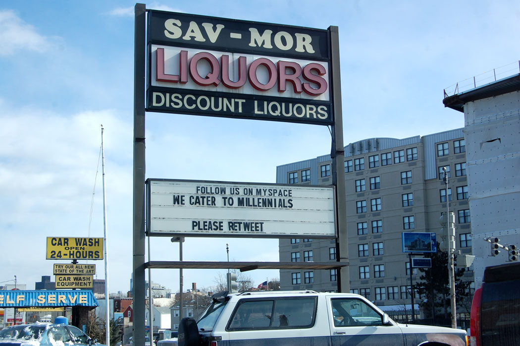 "Follow us on Myspace / We cater to Millenials / Please retweet" sign at Sav-Mor Liquors in Somerville, March 11, 2017. (Greg Cook)