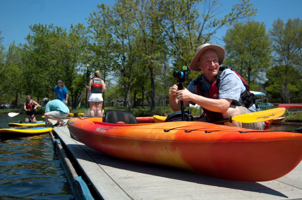 Cambridge artist Richard Hackel prepares to kayak the Charles River to photograph all 5 miles of the Cambridge shoreline turn it into a 500-foot-long panoramic photo mural, May 18, 2017. His “Cambridge Riverfront Panalateral” now adorns the construction site along Cambridge Street between Berkshire and Willow Streets where Cambridge’s new King Open and Cambridge Street Upper Schools and Community Complex is being built. (Greg Cook/Cambridge Arts Council)