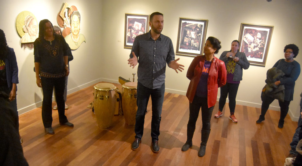 Andrew Mroczek, associate director of exhibitions at Lesley University, introduces curator Dell M. Hamilton (in red coat) at the opening reception for “SayHerName: Watch Us WERK” at Lesley University College of Art and Design’s VanDernoot Gallery in Cambridge, March 29, 2018. (Greg Cook)