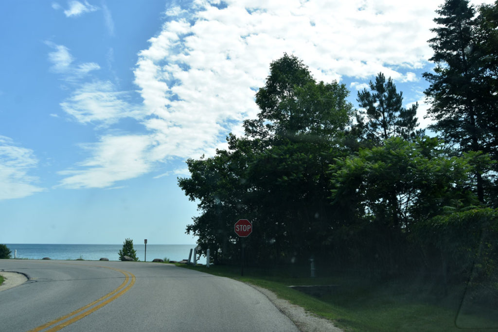 The lakeshore road that curves in front of Mary Nohl's home at Fox Point, Wisconsin, with the columns she crafted with her father. (She added the heads on top much later.) July 9, 2018. (Greg Cook)