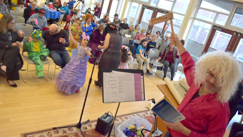 Rabbi Steven Lewis (right) shakes the granger during the reading of the megillah at the Purim Party at Gloucester's Temple Ahavat Achim, March 20, 2019. (Greg Cook)