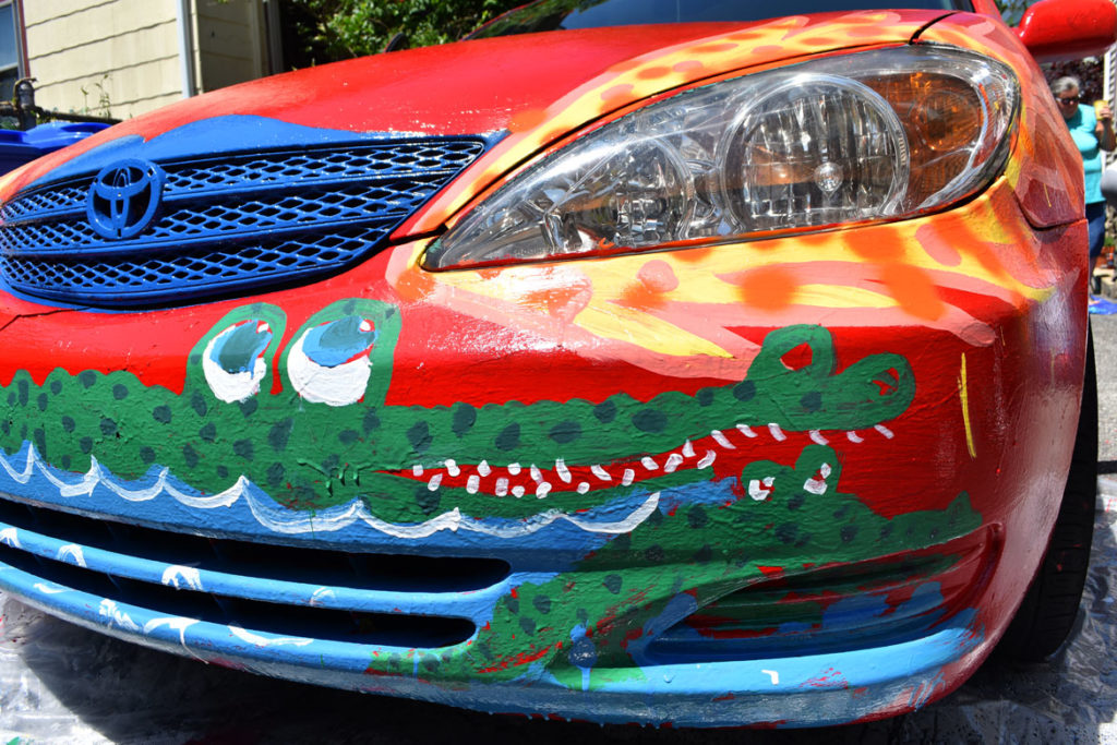 Painting Mark Alston-Follansbee's Toyota Camry art car in the driveway of his Waltham home, July 7, 2019. (Greg Cook)