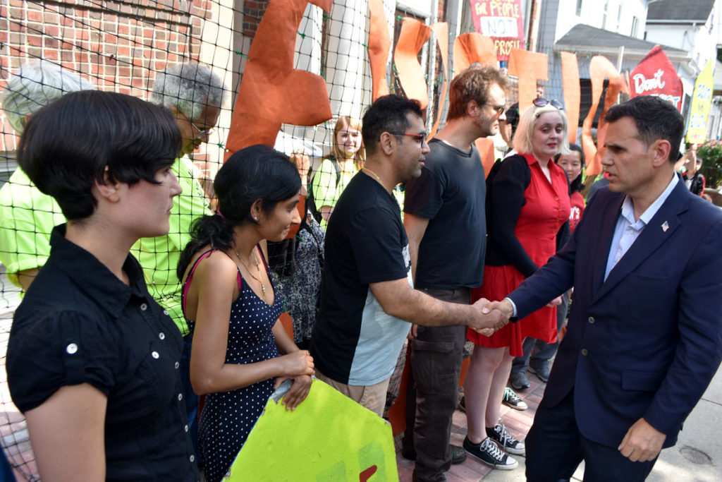 Malden Mayor Gary Christenson (right) shakes hands of tenants during a City Life/Vida Urbana rally to support renters fighting hikes of nearly 50 percent at 33 Park St., Malden, Aug. 3, 2019. (Greg Cook)