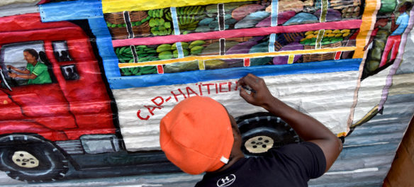 Pascal Michel paints his mural on the side of Highland Creole Cuisine, 2 Highland Ave., Somerville, Aug. 28, 2019. (Greg Cook)