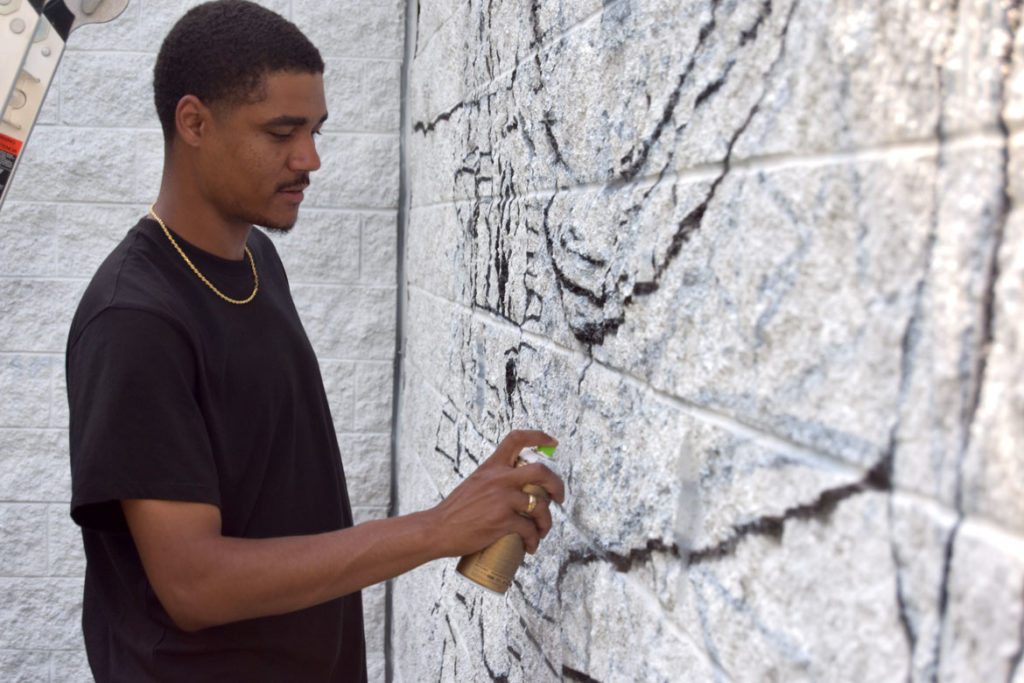 Curtis Williams begins a mural at Boston's Madison Park Technical Vocational High School, July 5, 2020. (© Greg Cook photo)