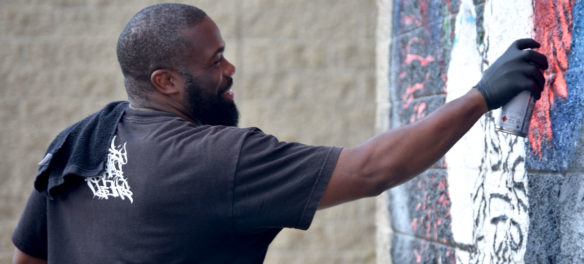 Rob "ProBlak" Gibbs paints his "Breathe Life" mural at Boston's Madison Park Technical Vocational High School, July 5, 2020. (© Greg Cook photo)