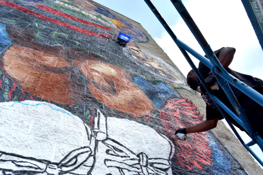 Rob "ProBlak" Gibbs paints his "Breathe Life" mural at Boston's Madison Park Technical Vocational High School, July 5, 2020. (© Greg Cook photo)