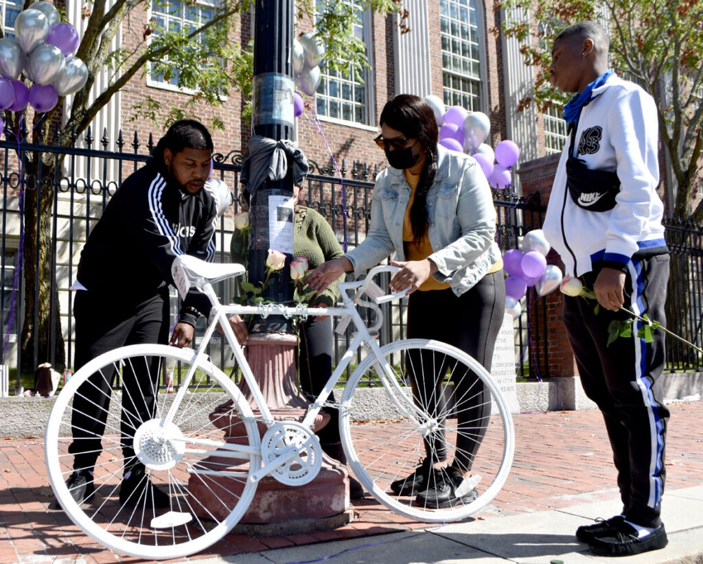 Family members of Darryl Willis, who was fatally struck by a truck in Cambridge's Harvard Square on Aug. 18, place flowers on a ghost bike set there in his memory on Sept. 19, 2020. (© Greg Cook photo)