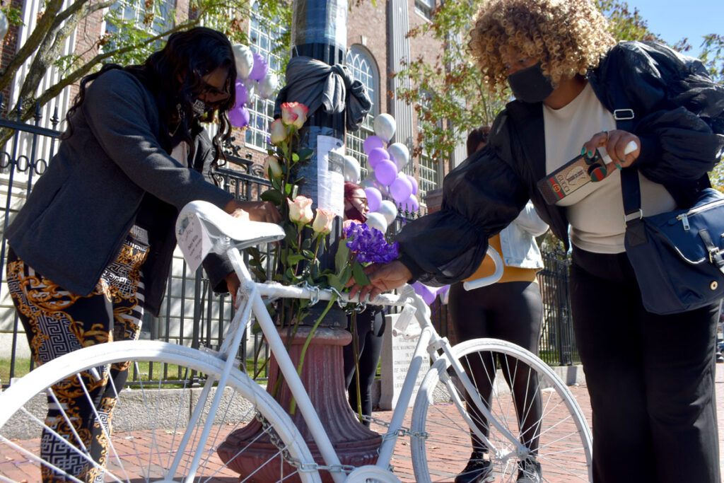Family members of Darryl Willis, who was fatally struck by a truck in Cambridge's Harvard Square on Aug. 18, place flowers on a ghost bike set there in his memory on Sept. 19, 2020. (© Greg Cook photo)