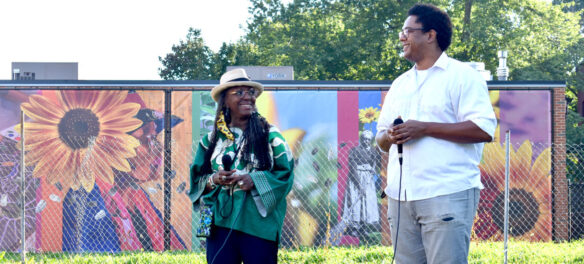 Ekua Holmes (left) and London Parker-McWhorter talk about there temporary, printed murals "Honoring the past, seeding the future,” at Breeze’s Laundromat at 345 Blue Hill Ave., Boston, Sept. 8, 2021. (©Greg Cook Photo)