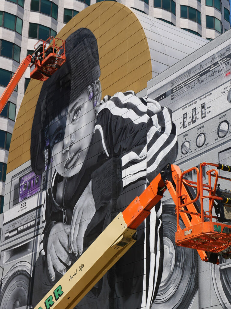 Rob “ProBlak” Gibbs at work on his "Breathe Life Together" mural at Dewey Square on Boston's Greenway, June 14, 2022. (©Greg Cook photo)
