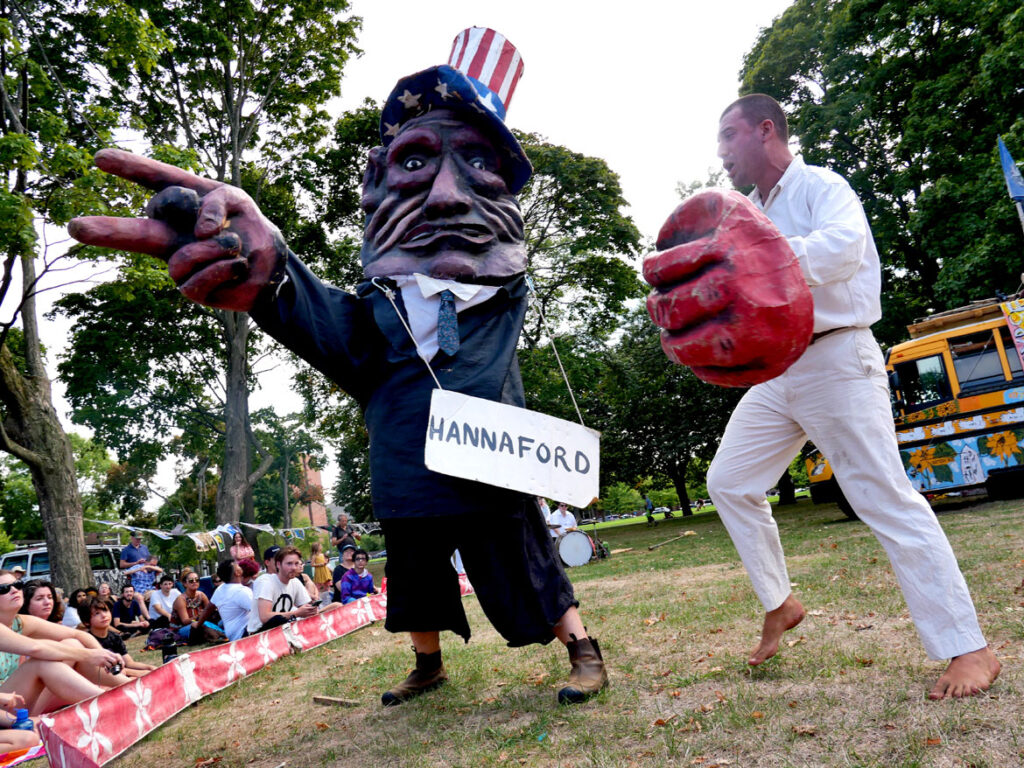 Bread and Puppet Theater performs an act accusing Hannaford of being unfair to farm workers. From its “Apocalypse Defiance Circus” on Cambridge Common, Sept. 4, 2022. (© Greg Cook photo)
