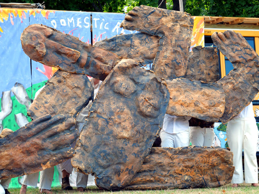 Bread and Puppet Theater performs an act calling for reparations for Haiti. From its “Apocalypse Defiance Circus” on Cambridge Common, Sept. 4, 2022. (© Greg Cook photo)