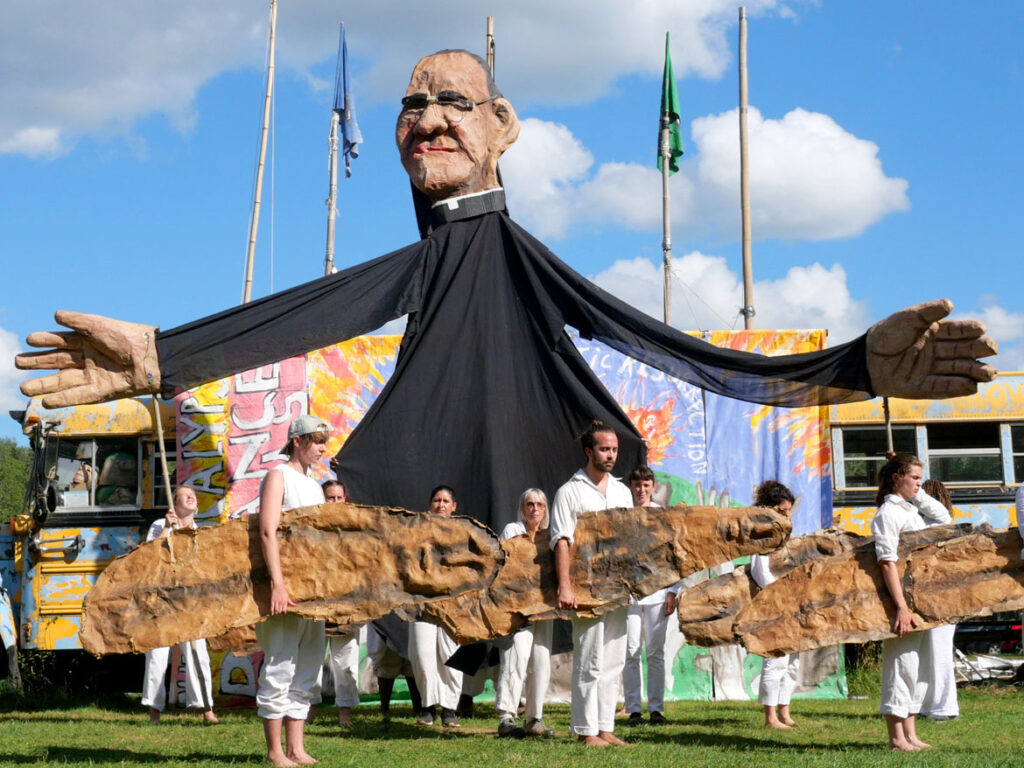 Bread and Puppet Theater's act about the 1980 murder of Archbishop Oscar Romero in El Salvador. Part its "Apocalypse Defiance Circus" in Glover, Vermont, Aug. 28, 2022. (© Greg Cook photo)
