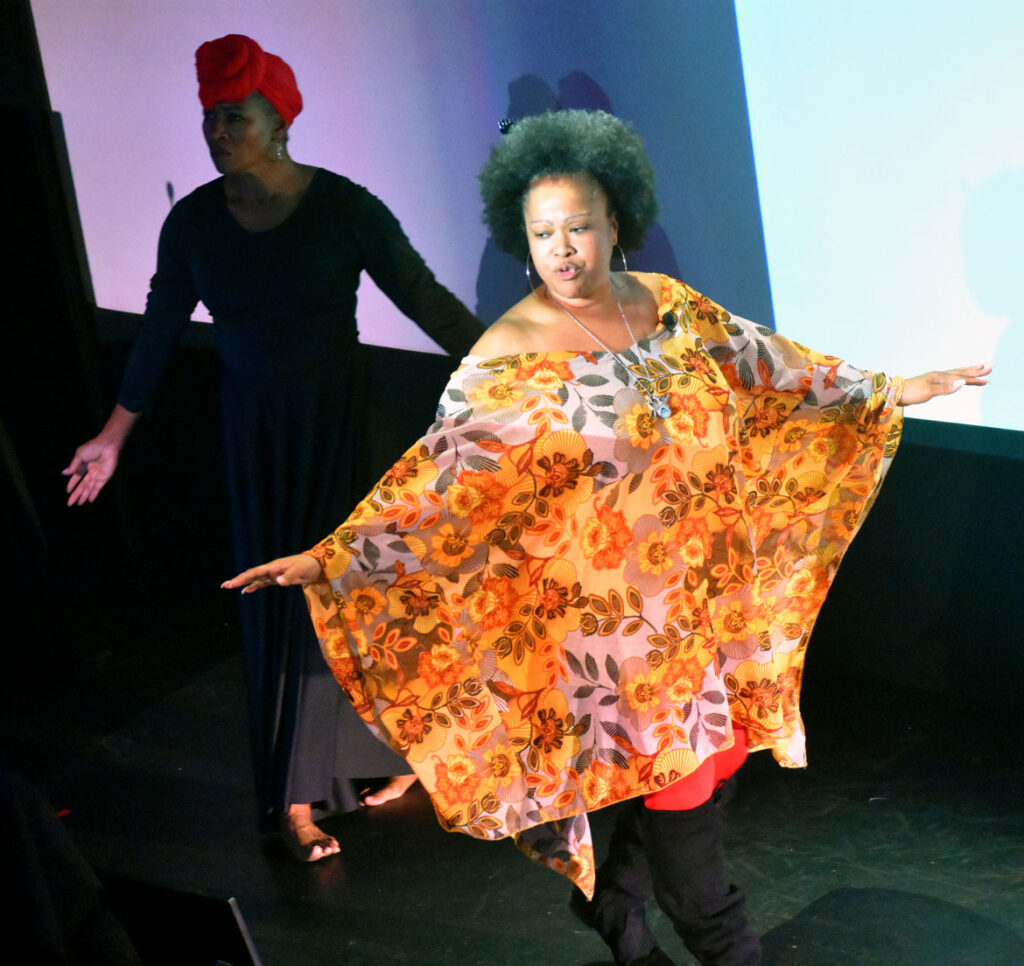 Poet Michelle La Poetica (right) and dancer Lisa Miller-Gillespie perform at the Arts & Culture Summit from the Essex County Community Foundation's Creative County Initiative at The Cabot theater in Beverly, Sept. 30, 2022. (©Greg Cook photo)