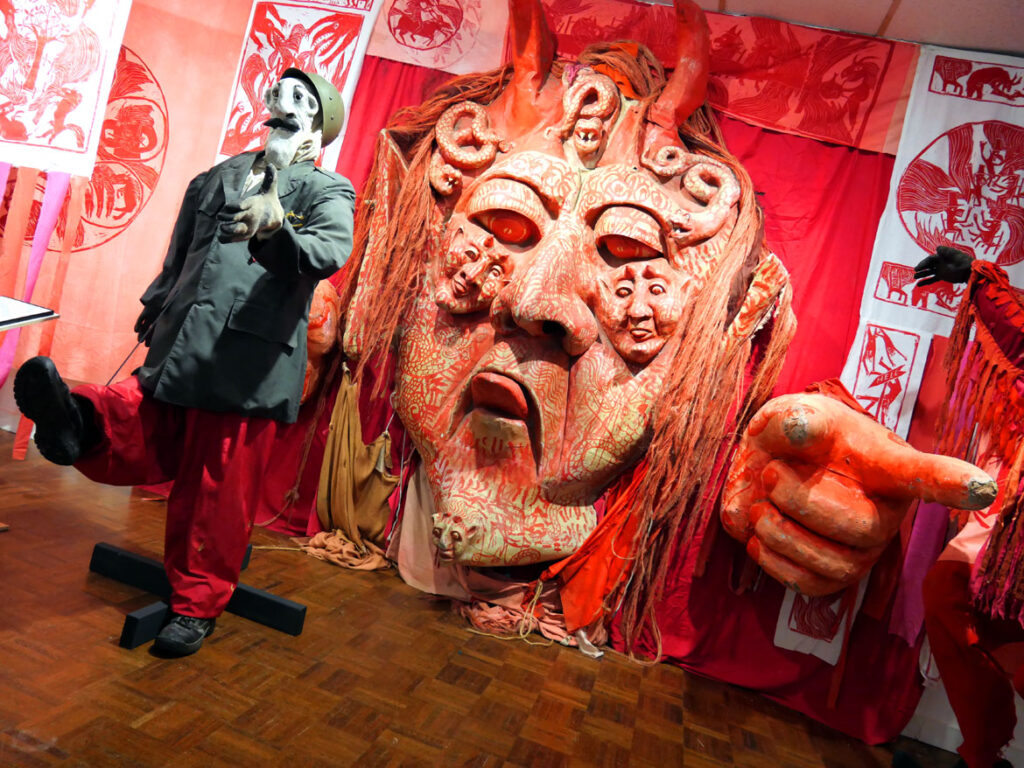 Puppets, costumes and woodcut banners from the 1971 performance “The Birdcatcher in Hell” in the exhibition “Bread and Puppet Theater: Art and Activism in Five Acts” at Salem State University, November 2022. (©Greg Cook photo)