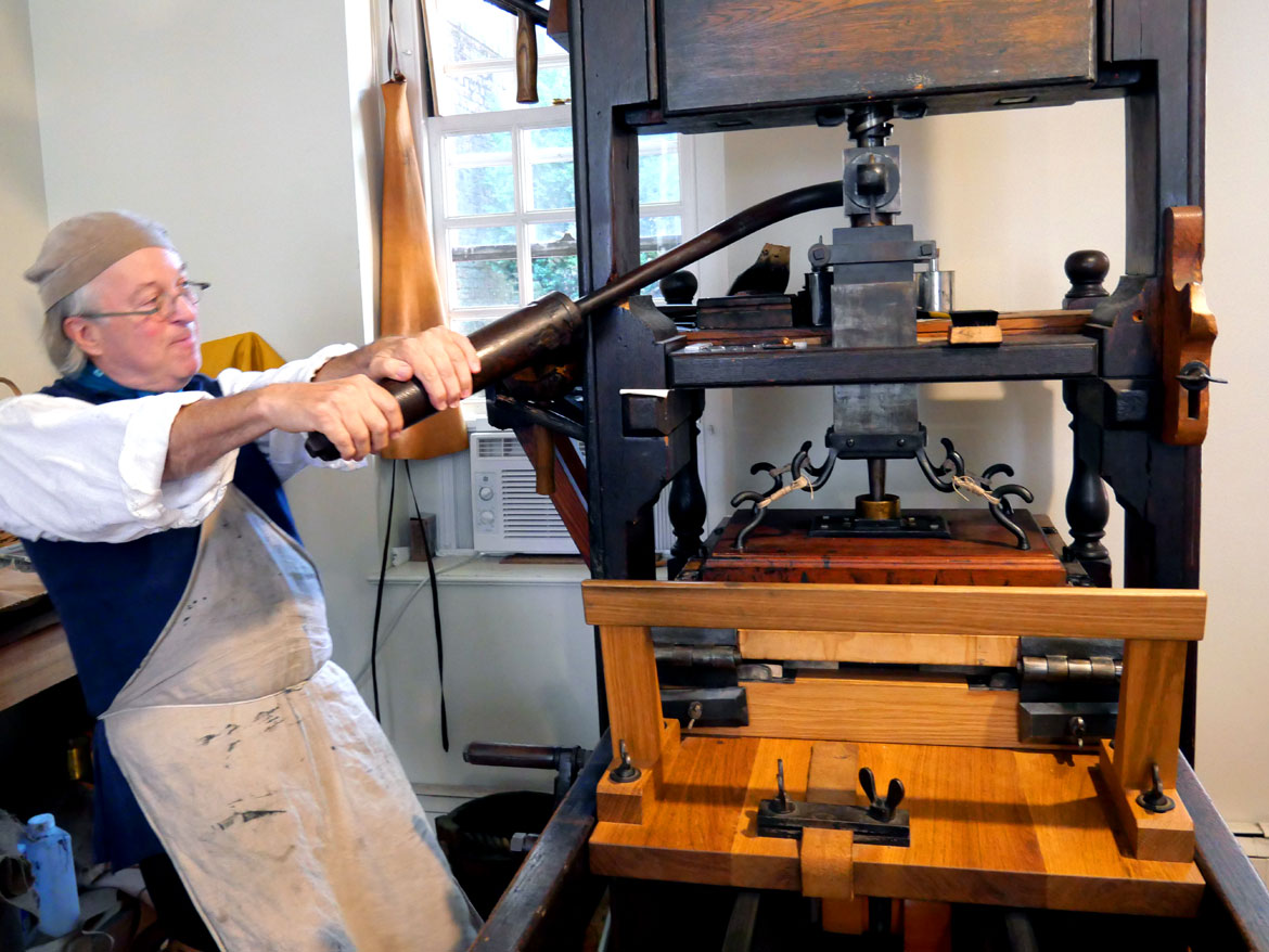 Gary Gregory operates his reproduction 18th century press in the Printing Office of Edes & Gill, in the 1715 Clough House o the campus of Boston's Old North Church, Aug. 13, 2023. (©Greg Cook photo)