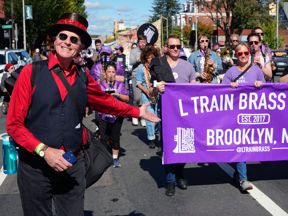 Honk co-organizer John Bell (left) with the L Train Brass Band from Brooklyn in the Honk Parade, Oct. 8, 2023. (©Greg Cook photo)
