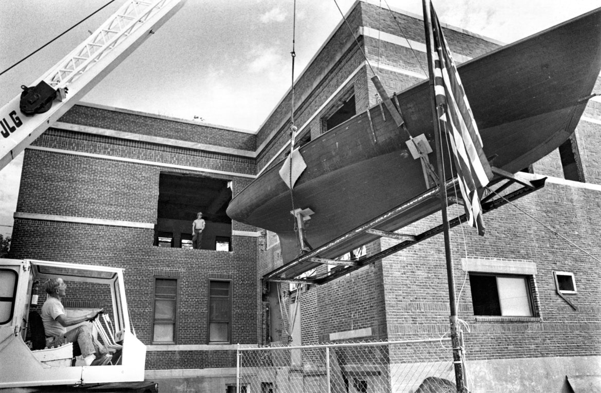 "Great Republic, Howard Blackburn’s sloop, is lifted by crane on Thursday into its new home, the former phone building on Elm Street, which is being converted into part of the Cape Ann Historical Association," Aug. 1, 1992. Photograph by Cristin Gisler. In "Above the Fold" at the Cape Ann Museum, 2023.