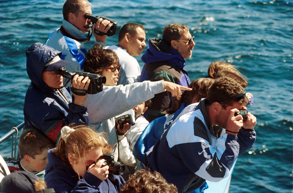 "Passengers crowd the pulpit of the Yankee Spirit, one of many charter boats that carry sightseers in search of whales during the summer months," June 15, 1997. Photograph by Josh Reynolds. In "Above the Fold" at the Cape Ann Museum, 2023.