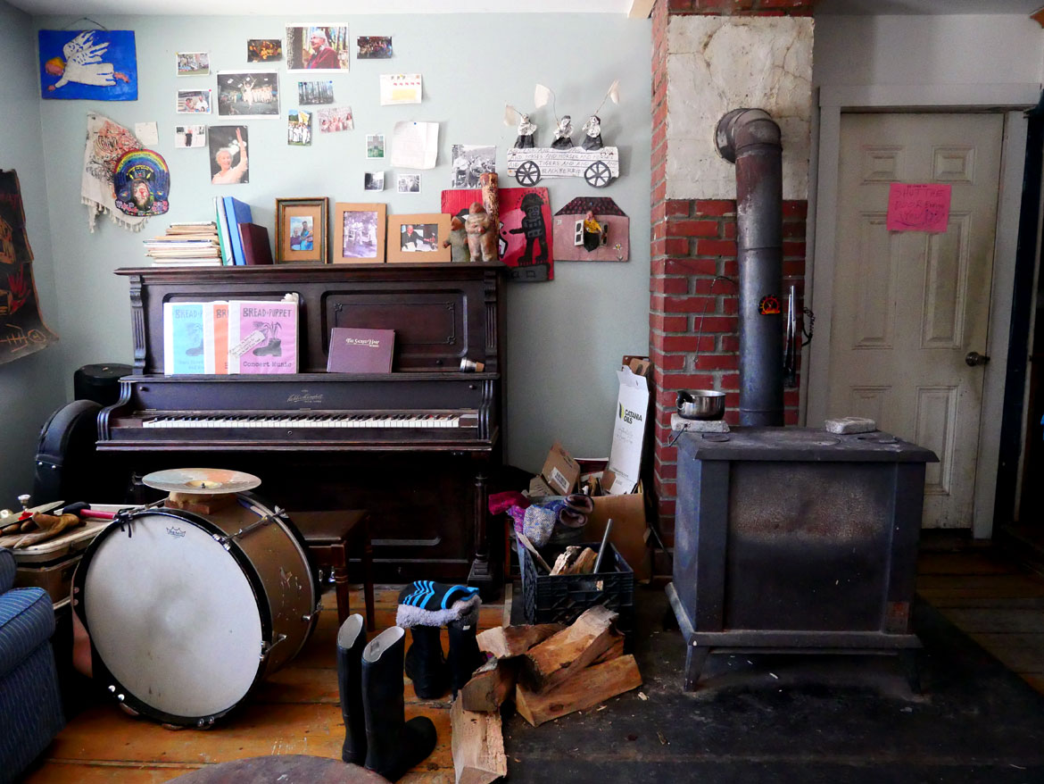 Piano and blazing wood stove in Puppeteer's House at Bread and Puppet Theater, Glover, Vermont, Feb. 9, 2026. (©Greg Cook photo)