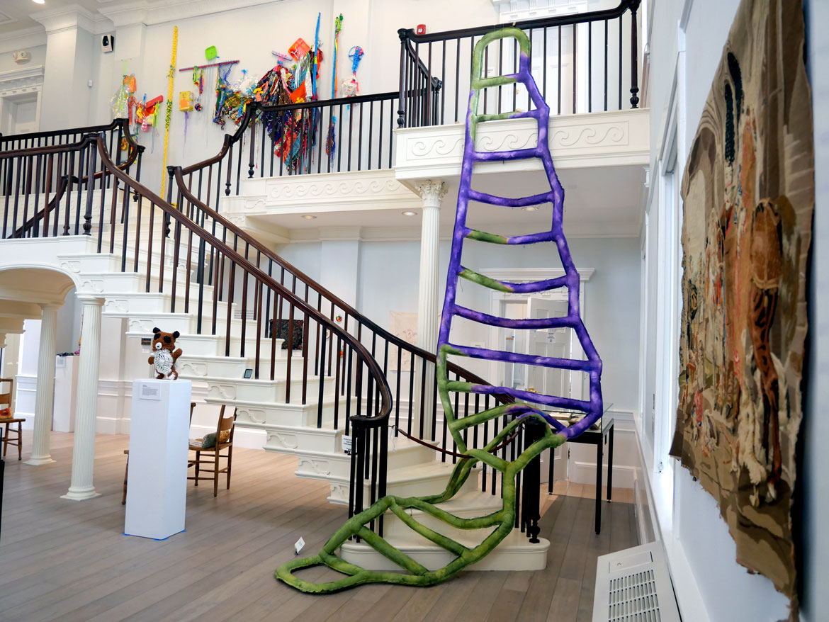 Kate Holcomb Hale, "Use Both Hands When Climbing. Do Not Overreach," 2026 (draped over stairs).