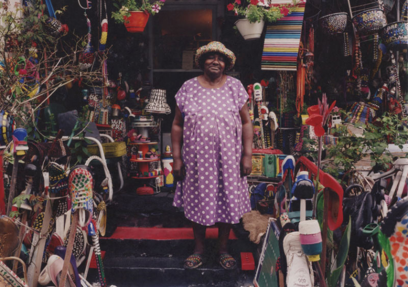 Mrs. L.V. Hull with Purple Polka Dot Dress. L.V. Hull surrounded by her art environment on her front porch in Kosciusko, Mississippi in 2002. (Photo: Bruce West)