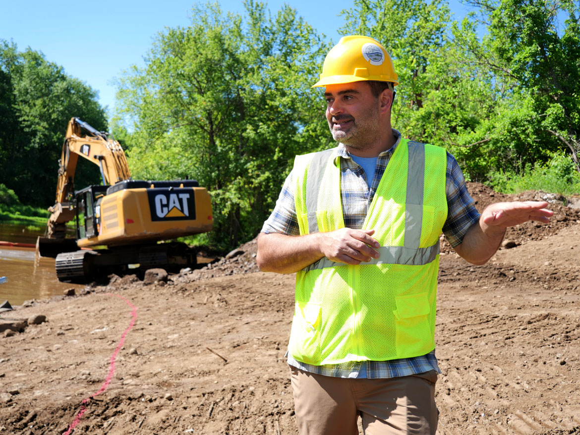 Joseph Gould, Restoration Specialist for Massachusetts Division of Ecological Restoration, on riverbank at the Wheelwright Dam, June 9, 2026. (©Greg Cook photo)