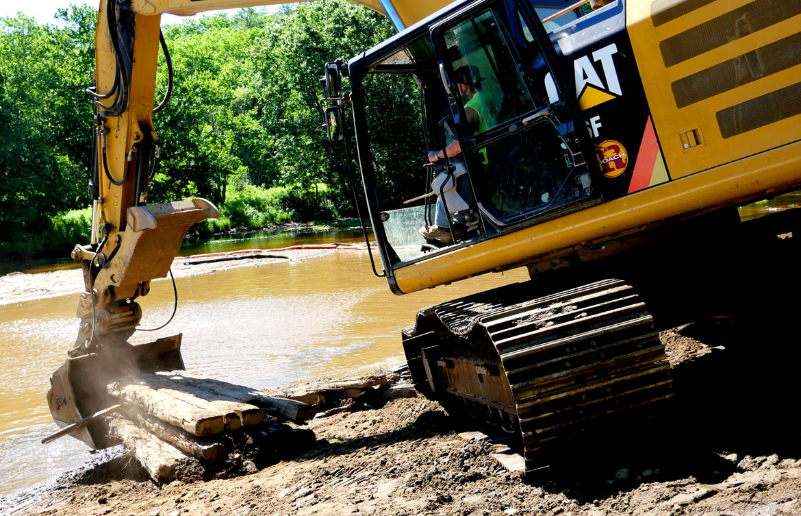 Earth mover moves timbers from the Wheelwright Dam, June 9, 2026. (©Greg Cook photo)