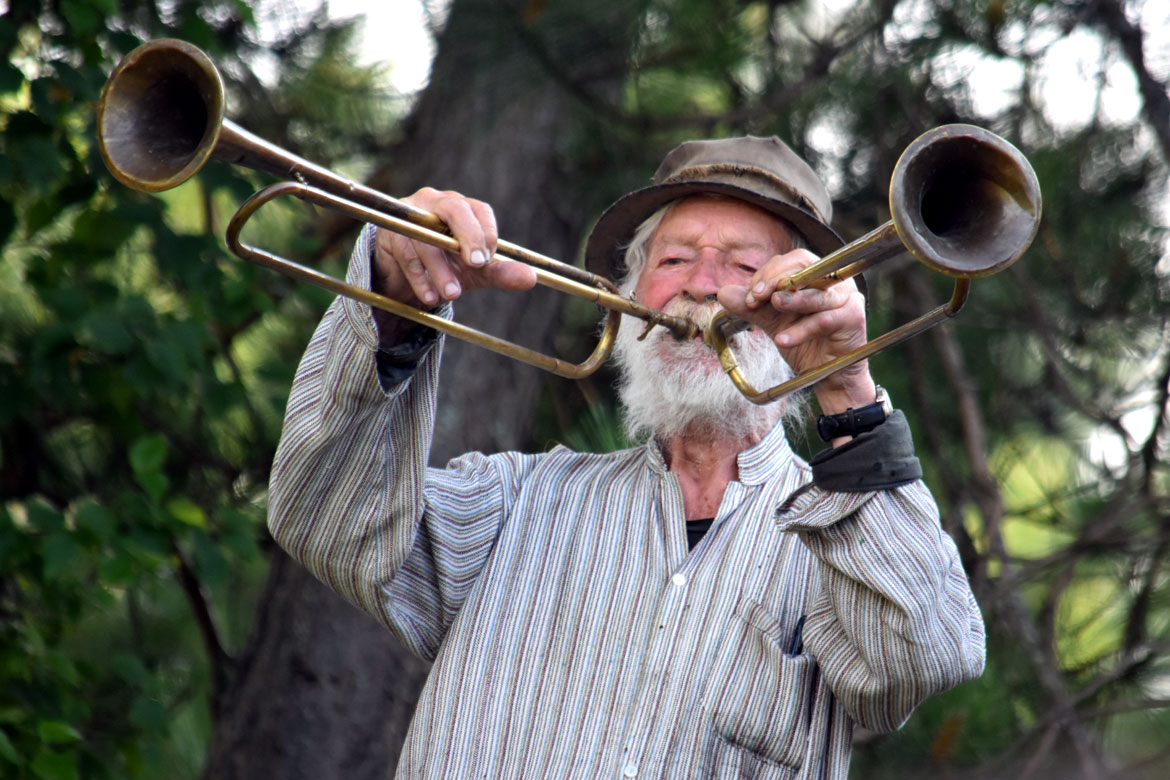 Peter Schumann plays trumpets during Bread and Puppet Theater's "Upside Down World Resurrection Pageant," performed on their Glover, Vermont, farm, July 26, 2026. (©Greg Cook photo)