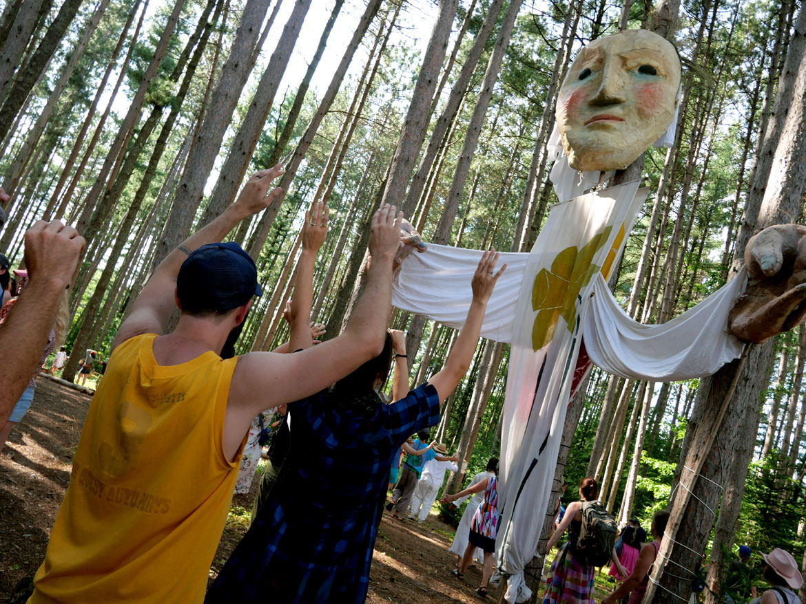 Long line dances in the Pine Forest during Bread and Puppet Theater's "Upside Down World Resurrection Pageant," performed on their Glover, Vermont, farm, July 26, 2026. (©Greg Cook photo)